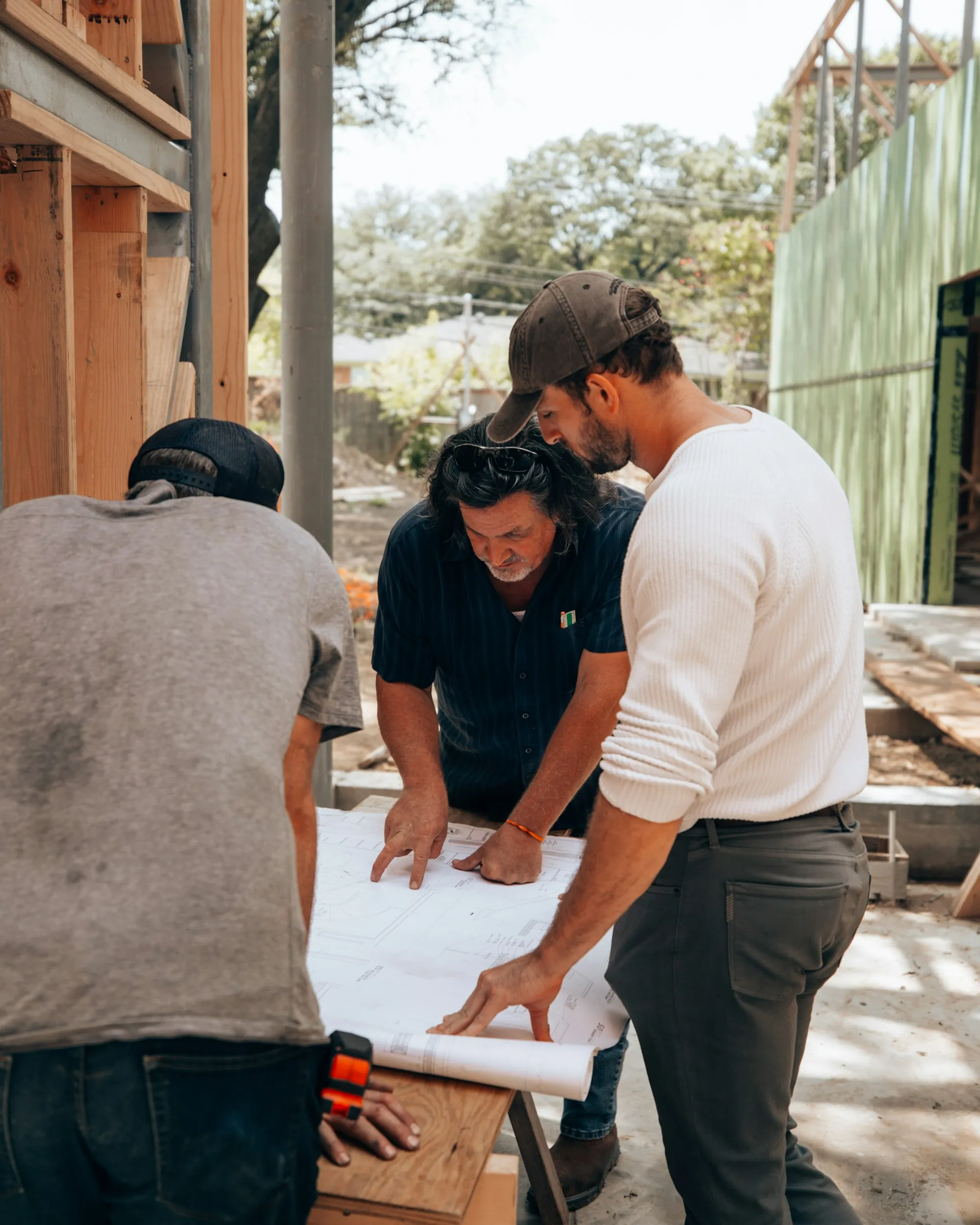 Three men looking over plans laid out on a table