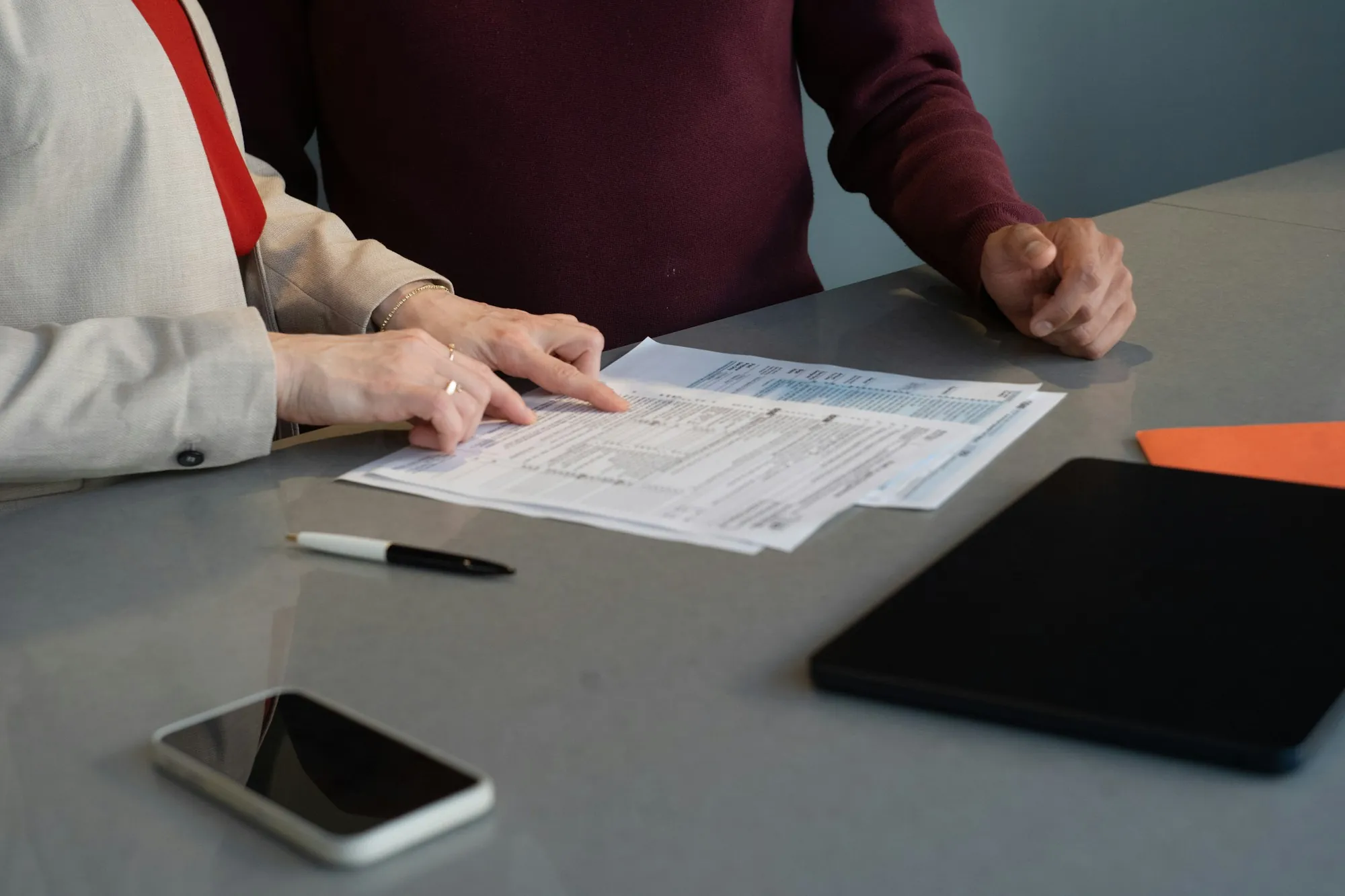 Two people reviewing a form at a table with a phone and tablet