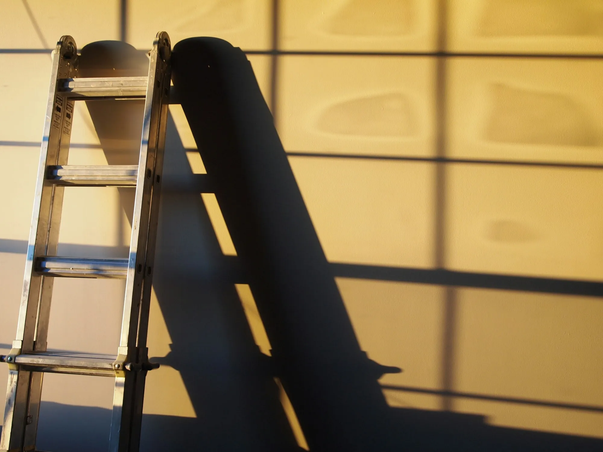 Aluminum step ladder against a wall in warm light